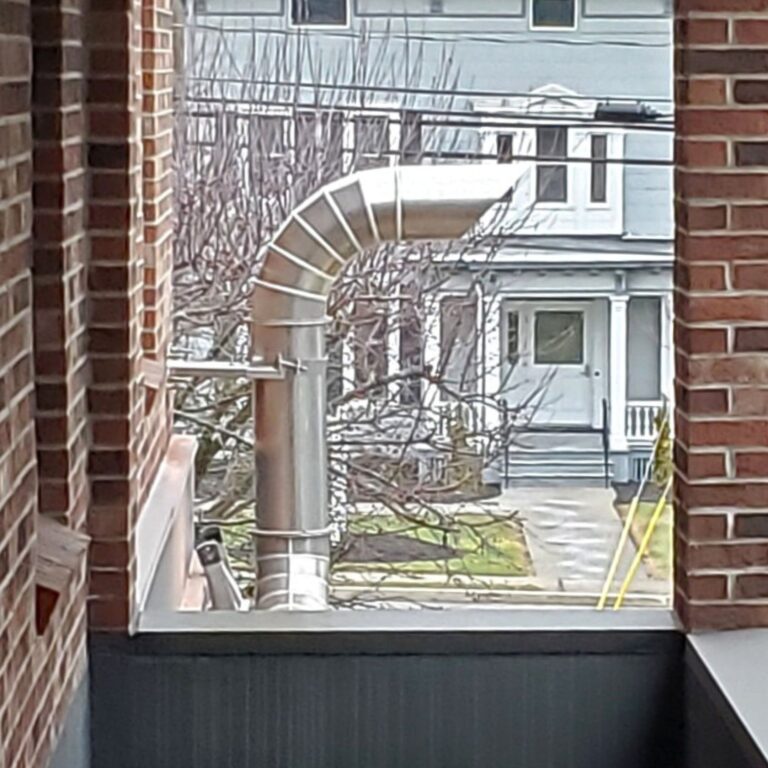 Non magnetic vent exhaust pipe with a gentle curve, secured near the building perimeter.