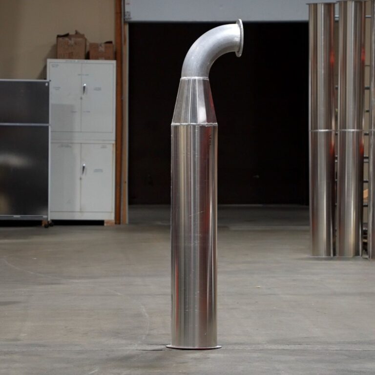 Modular stainless steel elbow component of the MRI quench exhaust system on concrete floor.