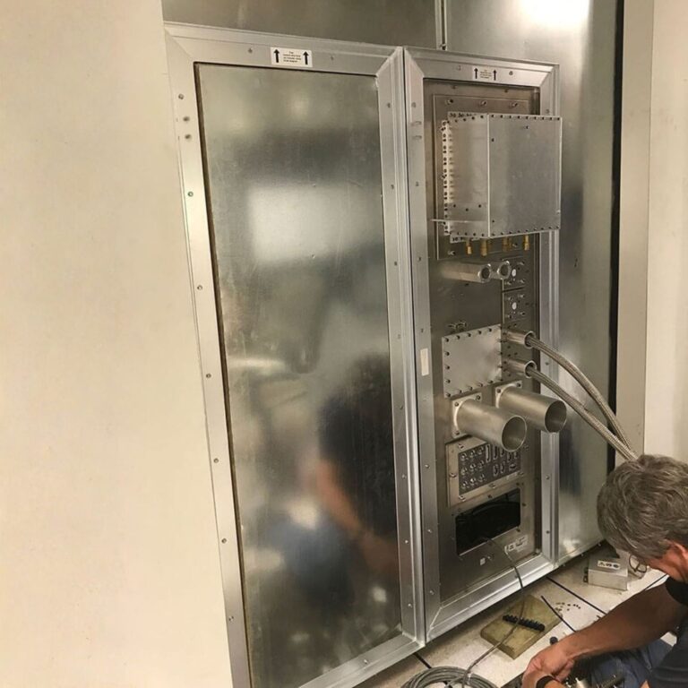 Integrated RF shield penetration panel under final installation, connecting multiple shielded services and ports.