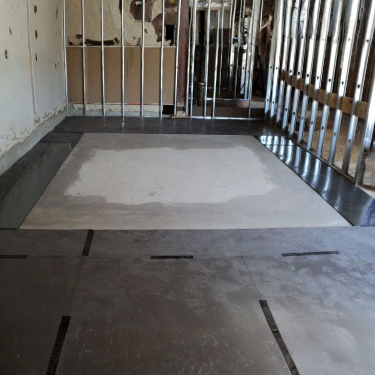 Metal RF shielding floor panels laid over concrete, showing perimeter wall framing.