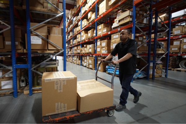 Warehouse worker moving medical imaging equipment parts for distribution and shipping.
