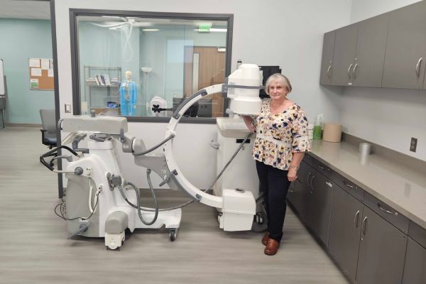 Professional standing by Skanray C arm X ray machine in modern medical imaging and procedure suite.