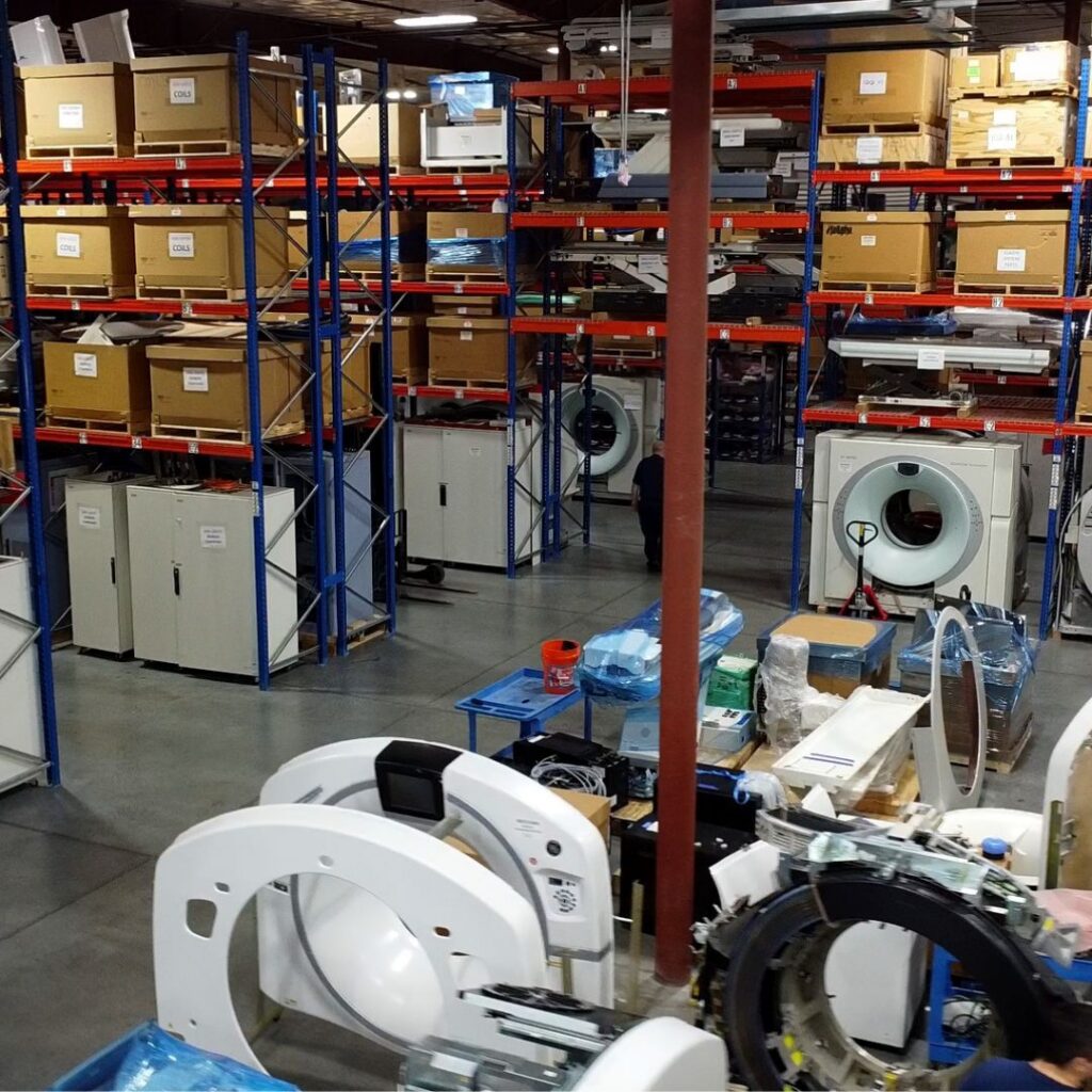 High-capacity warehouse shelving with CT scanner gantries and medical imaging replacement parts.