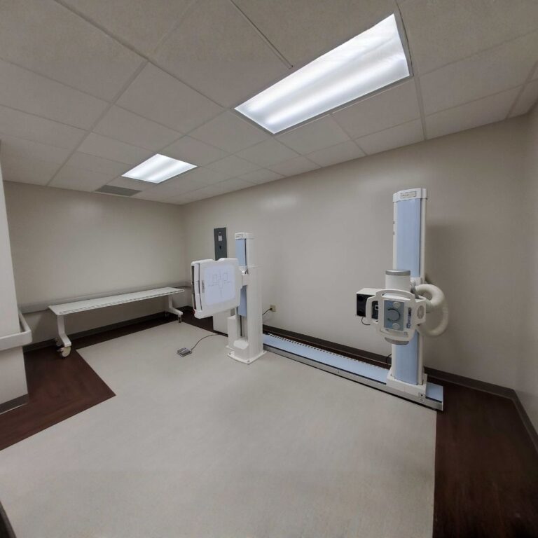 Fully positioned floor-rail X-ray system in a large, updated orthopedic room.
