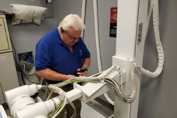 Specialized technician performing X ray repair and preventative maintenance on diagnostic imaging equipment.
