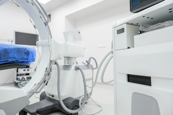 clinical exam room with professional C arm X ray machine and patient table with blue drape.