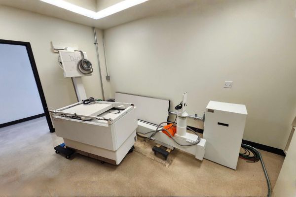 Partially disassembled X-ray table and components staged for relocation.
